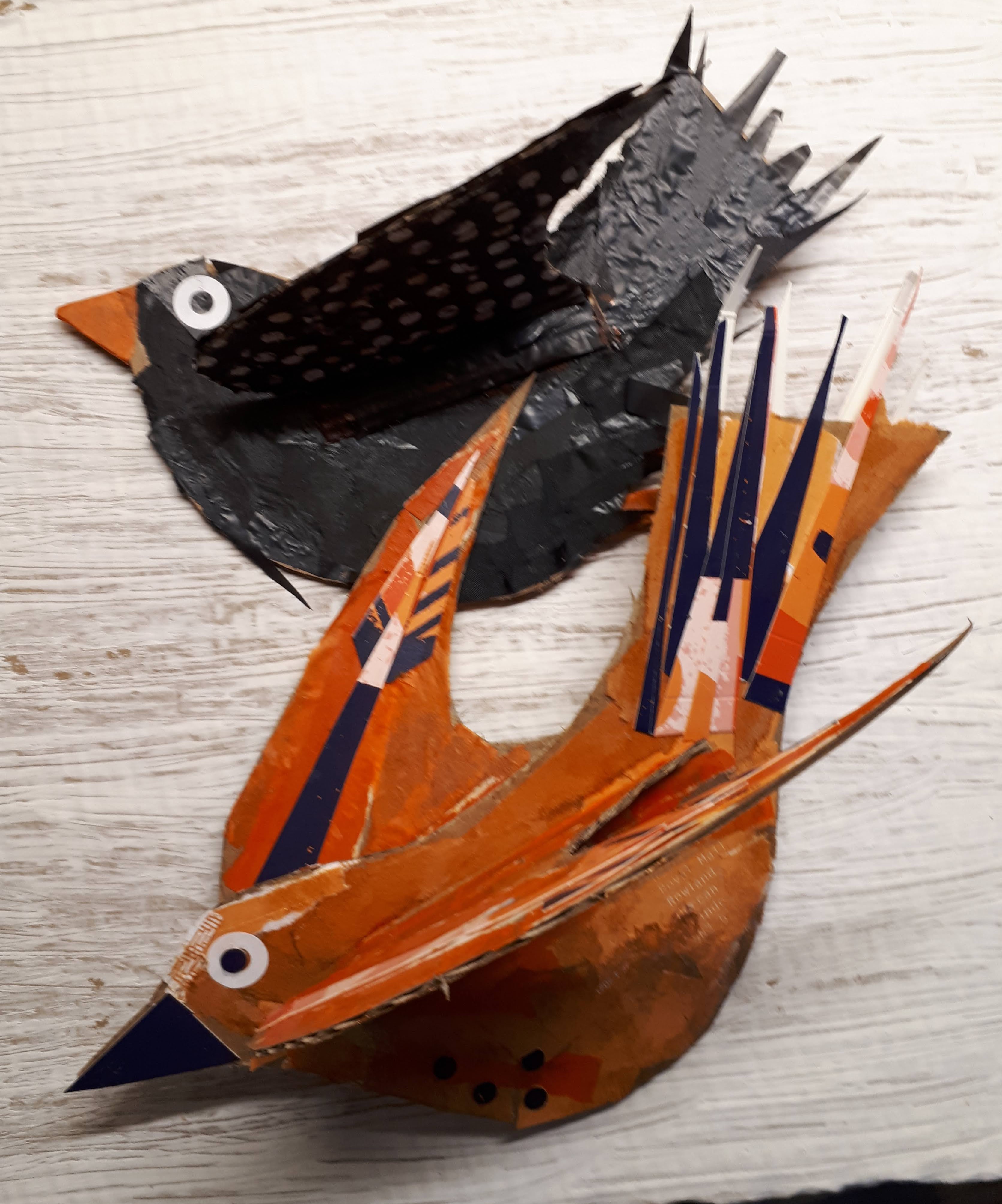 A blackbird and an orange bird made from painted cardboard