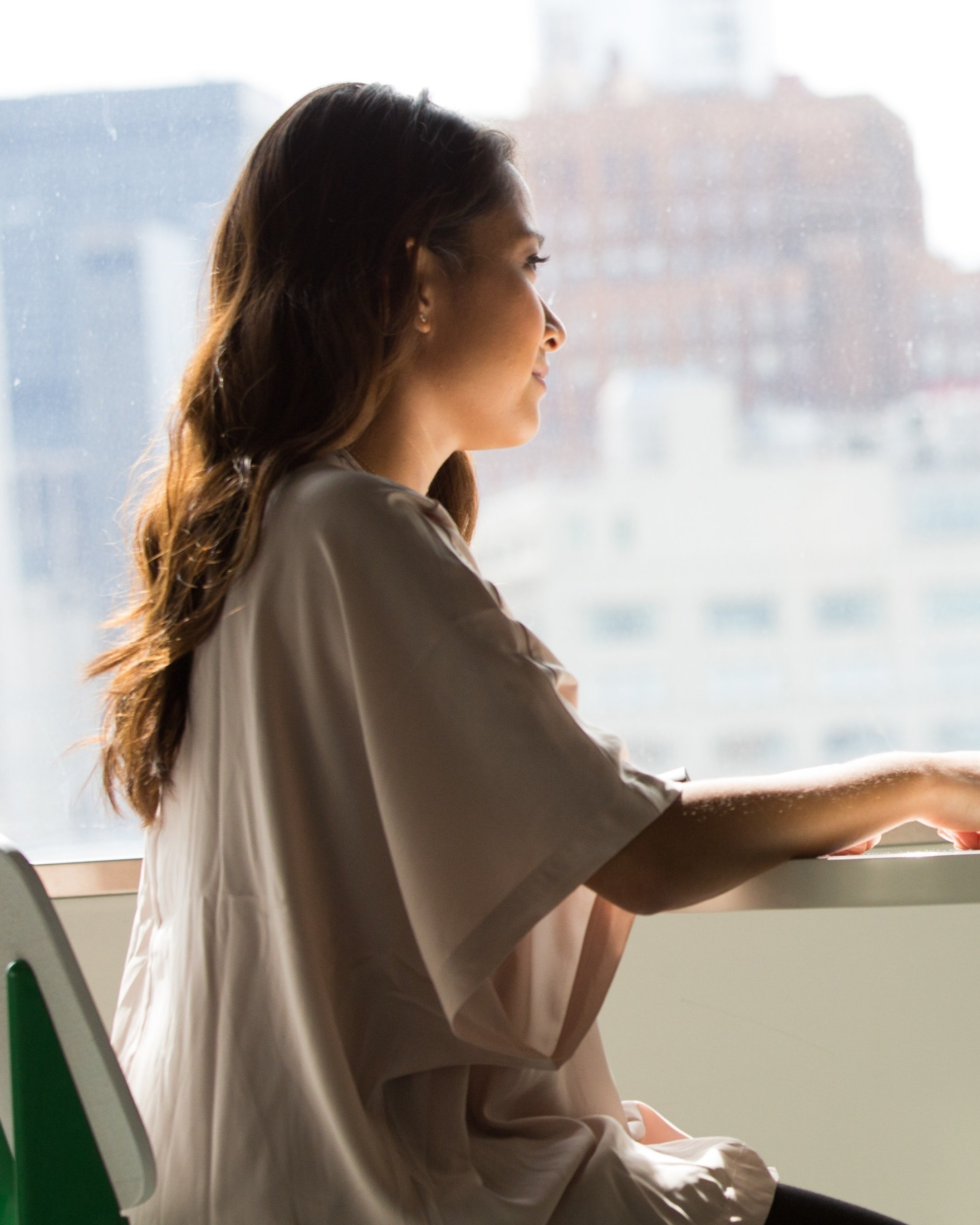 A woman sat at a white table with a cityscape behind her.